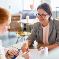 Smiling employer looking at applicant and showing her terms of contract